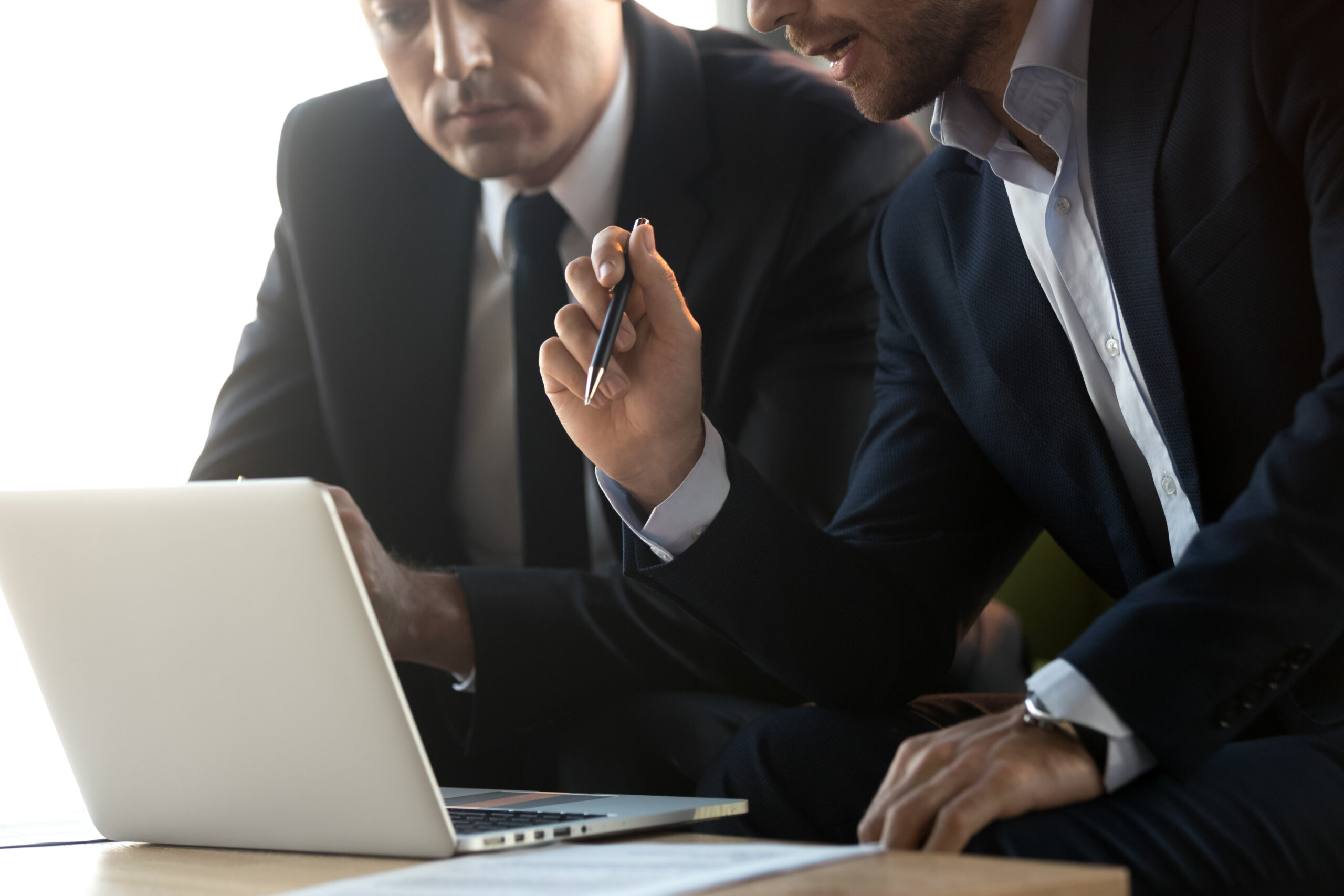 Serious,Businessmen,In,Suits,Talk,Work,Together,With,Laptop,,Financial